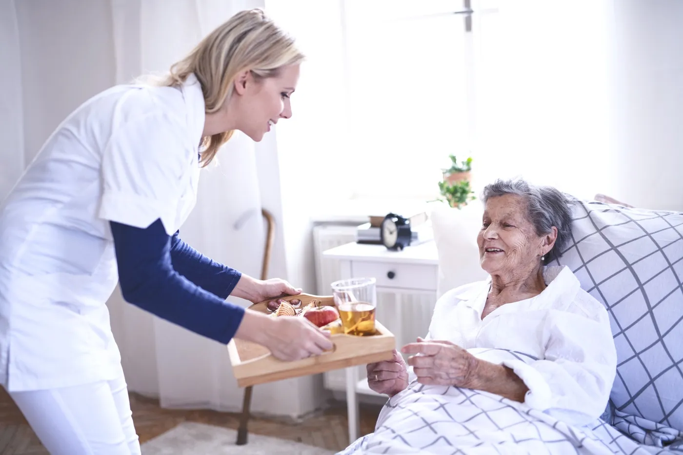 A Harmony carer bringing breakfast in bed to an elderly client